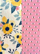 Load image into Gallery viewer, Two beeswax wraps side by side. One is floral, the other is a dark pink color with honeybees. 