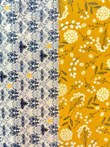 Two beeswax wraps side by side. One is black and white with honeybees, the other is a golden color. 